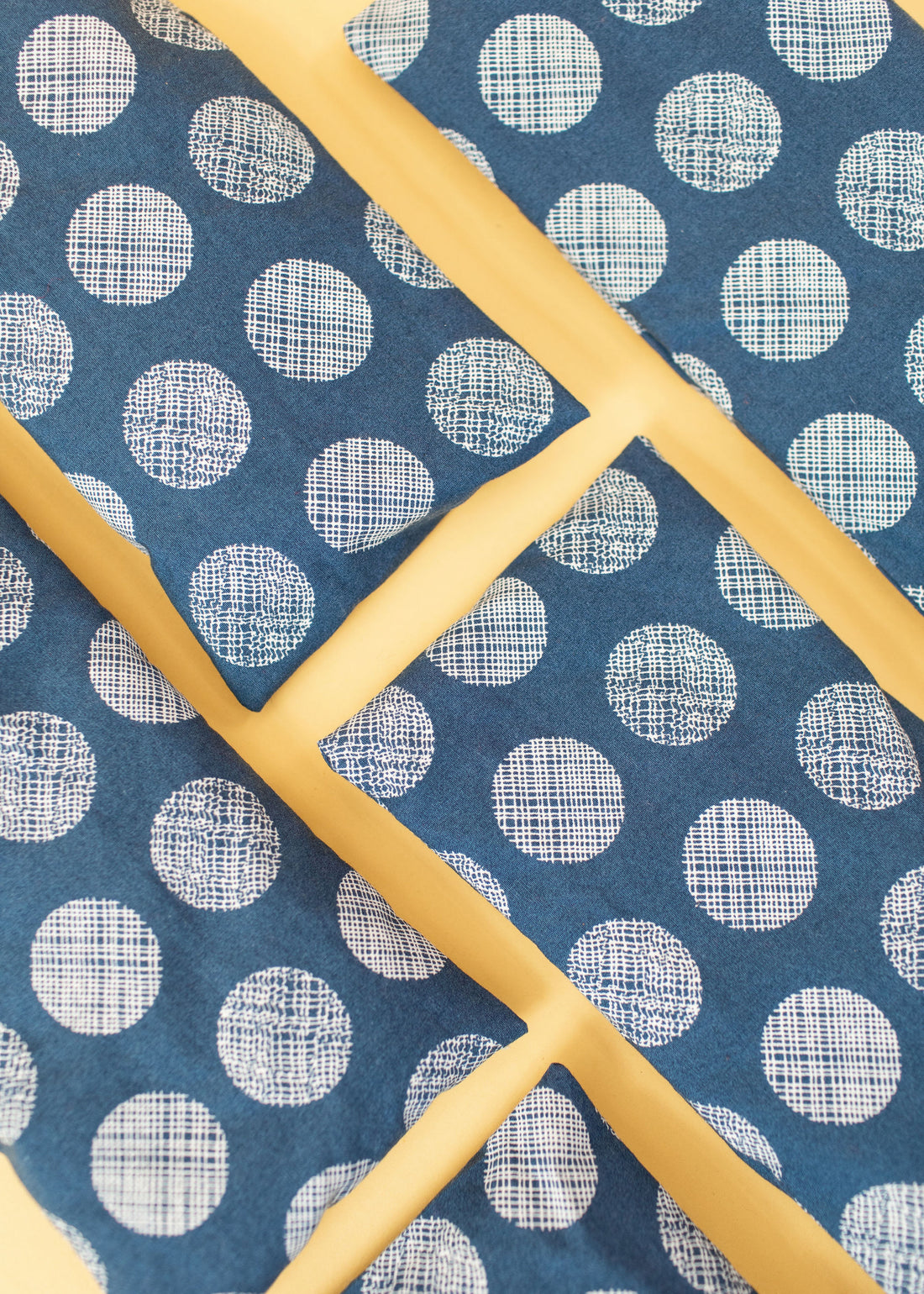 Eye pillow flat lays with a jean-blue colored fabric and white textured circles throughout.
