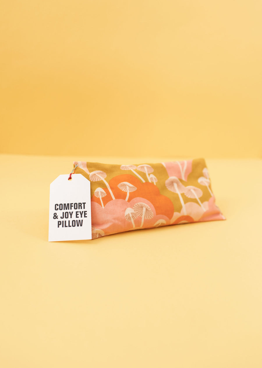 eye pillow with gold, pink and orange colors and white mushrooms on it