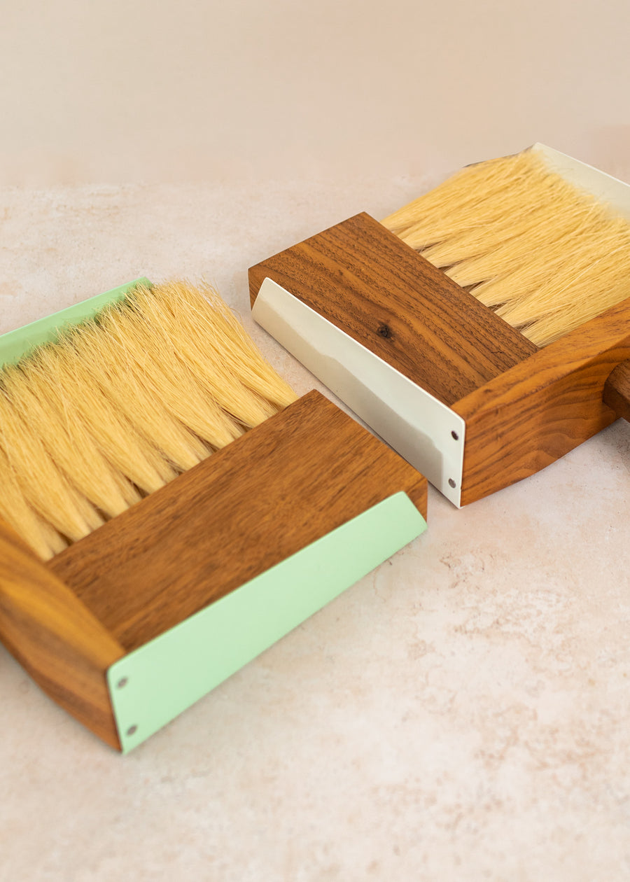 close up photo of two dust pan sets, one white farther away and the mint set closer to the camera.