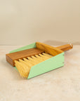 a mint green mini dust pan set on a pink background