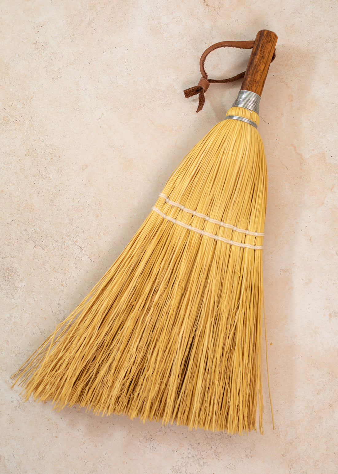 photo of a hand broom laying on a faint pink background