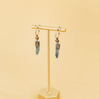 Two Claire Sommers Buck earrings on an earring stand