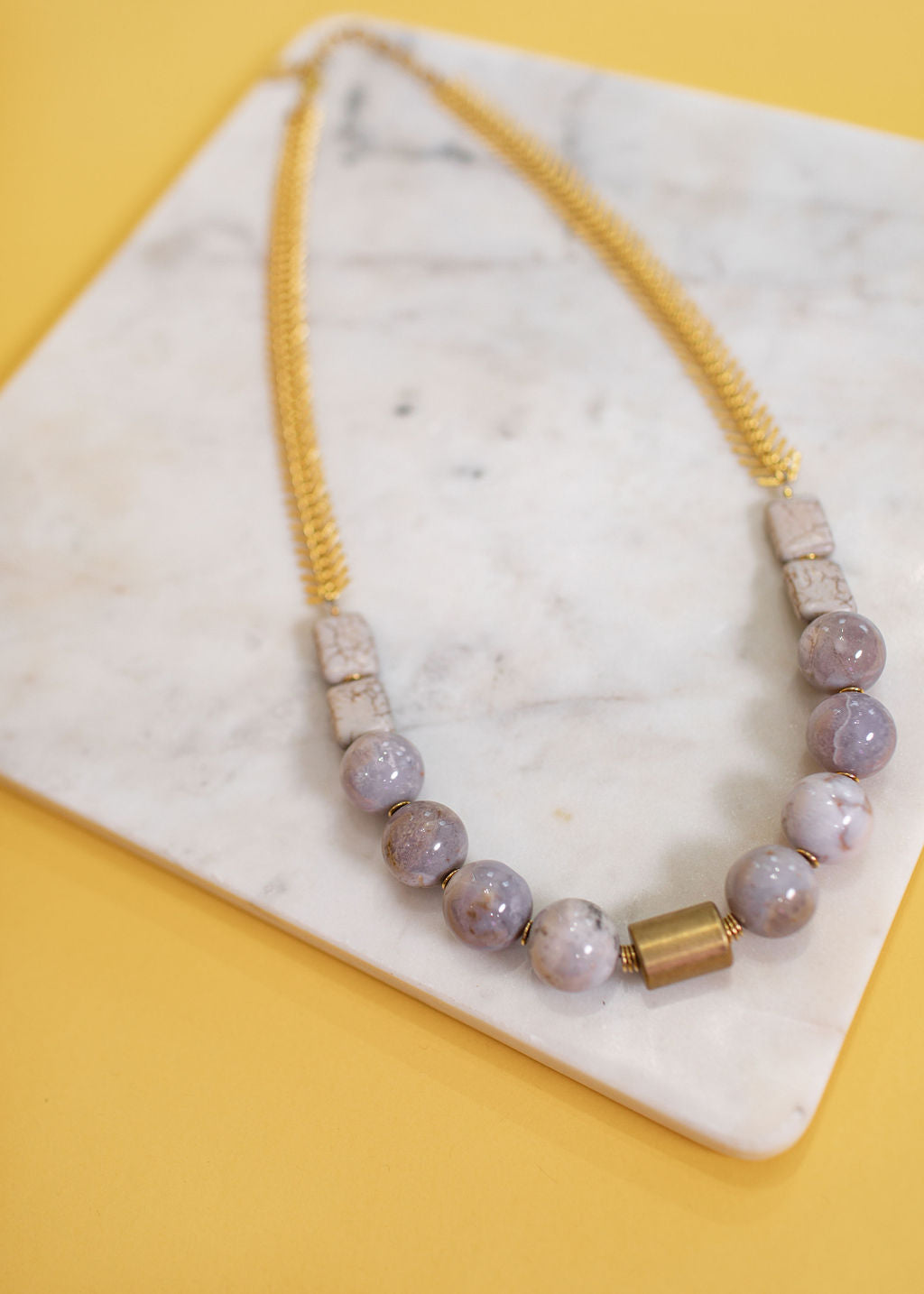 Lilac Stone and Fishbone Chain Necklace on a marble top