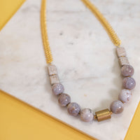 Lilac Stone and Fishbone Chain Necklace on a marble top