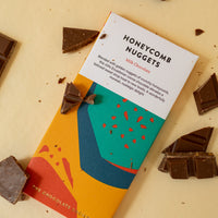 flatlay of a chocolate bar "honeycomb nuggets" with chocolate pieces scattered around, all on a yellow background