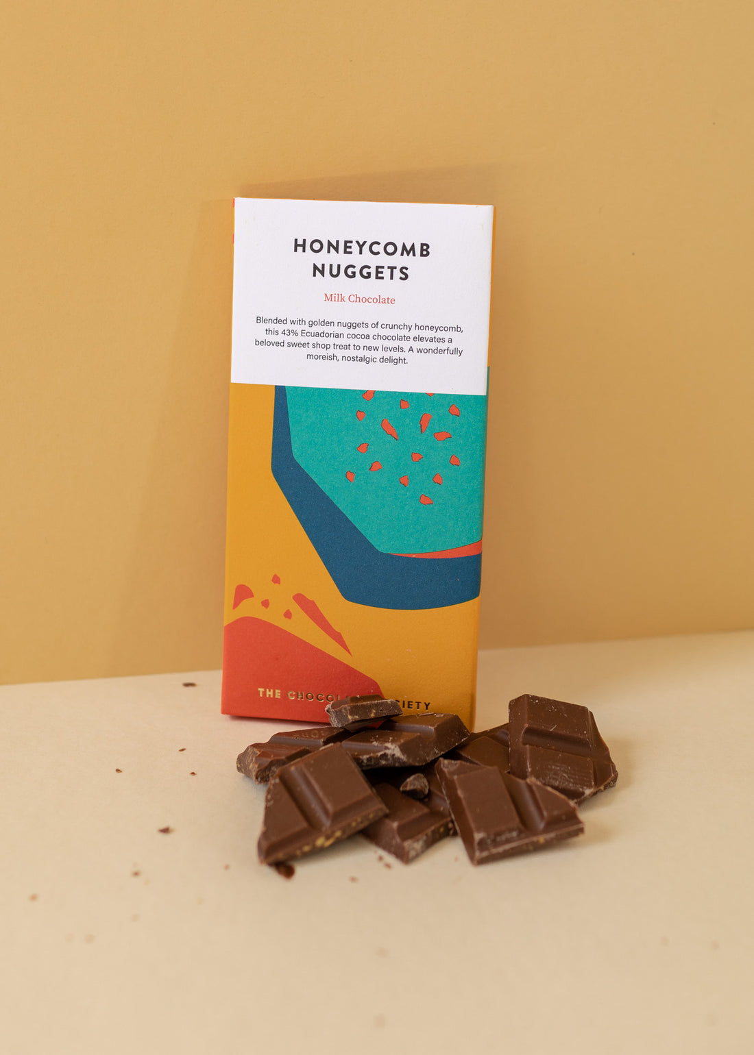  a chocolate bar "honeycomb nuggets" with chocolate pieces scattered on the ground, all on a yellow background
