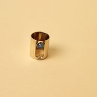 Long brass ring with an arch that take up some of the ring. inside arch is a round Labradorite stone